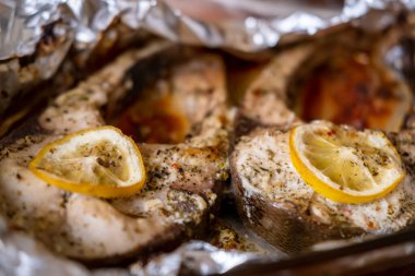 Baked fish silver carp steaks. Pieces of fish cooked in the oven in foil with lemon and spices.