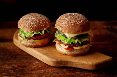 Ahşap arka planda iki hamburger. Büyük ve küçük çizburger. Hamburger günü..