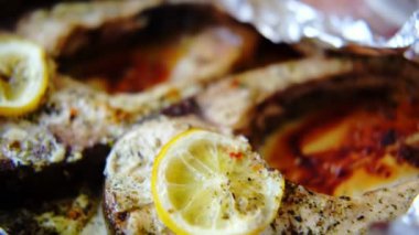 Baked fish silver carp steaks. Pieces of fish cooked in the oven in foil with lemon and spices.