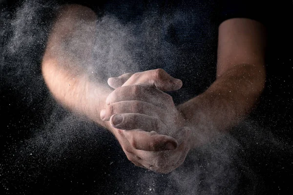 Homem Bate Palmas Com Mãos Espalhando Farinha Contra Fundo Escuro — Fotografia de Stock
