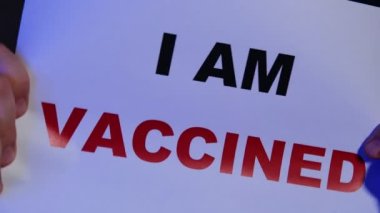 Aşılandım. Bir adamın elindeki bir kağıt parçasına yazılmış yazı..