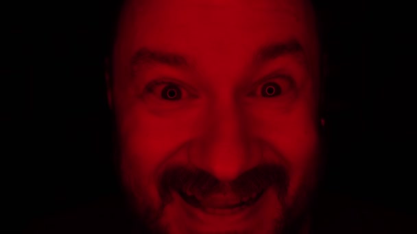 一个没有刮胡子的人发出的邪恶的笑声被红光照亮了 — 图库视频影像