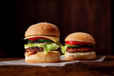 Ahşap arka planda iki hamburger. Büyük ve küçük çizburger. Hamburger günü..
