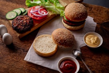 Ev yapımı hamburger ya da çizburger. Klasik bir hamburger için farklı malzemeler. Ahşap arka plan. Yiyecek konsepti.