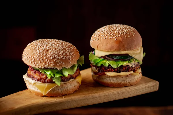 Ahşap arka planda iki hamburger. Büyük ve küçük çizburger. Hamburger günü..