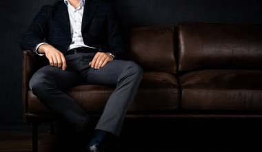 Tanınmayan stil sahibi maço adam karanlıkta koltukta rahatça oturuyor..