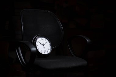 Teslim tarihi konsepti, zaman yönetimi. Siyah arka planda bir ofis sandalyesindeki saat.