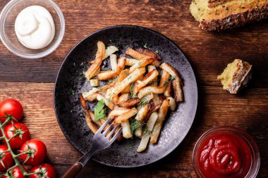 Eski ahşap bir zeminde, siyah bir tabakta fırında patates..