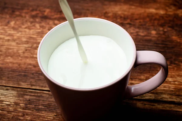 Latte Viene Versato Una Tazza Uno Sfondo Legno Marrone — Foto Stock