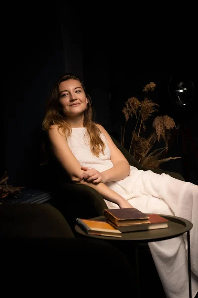 Uma Jovem Mulher Vestido Branco Sorri Senta Relaxada Uma Poltrona — Fotografia de Stock