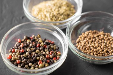 Üç konteynırda çeşitli baharatlar. Biber, kişniş, keklik otu. Karanlık arka plan. Yakın plan..