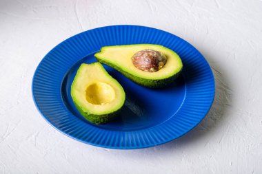 Sliced avocado on a blue plate. White background. Minimalism.