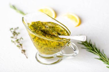 Beyaz arka planda soslu Chimichurri sosu. Arjantin vejetaryen sosu zeytinyağı, kekik, maydanoz.