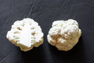 Karnabahar koyu bir arka planda ikiye bölünmüş. Vejetaryen yemeği, diyet konsepti.