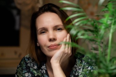 The middle-aged woman is tired. Surrounded by green plants. Burnout concept. Tired housewife.
