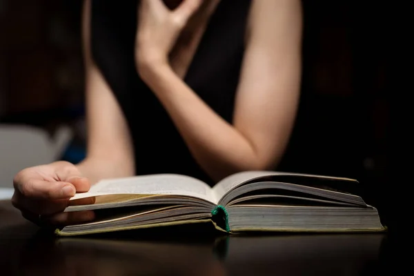 Uma Mulher Está Lendo Livro Escuro Senta Mesa — Fotografia de Stock