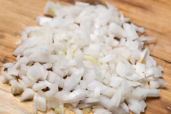 Diced onion on a wooden cutting board. Sliced white onion.