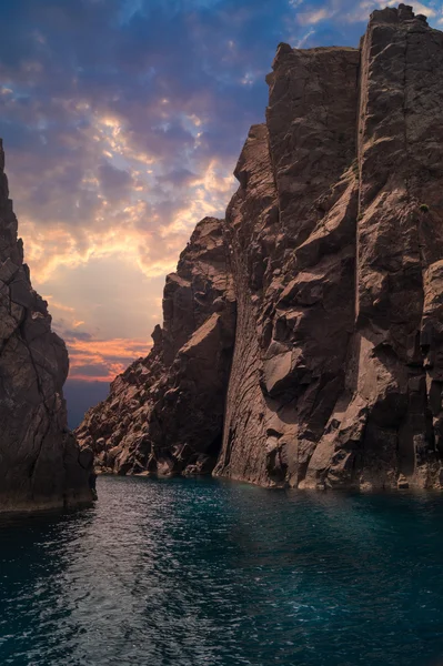Pôr do sol tropical através de rochas altas no Mar Egeu, Grécia — Fotografia de Stock