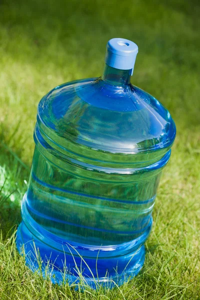 Água grande garrafa no fundo grama verde — Fotografia de Stock
