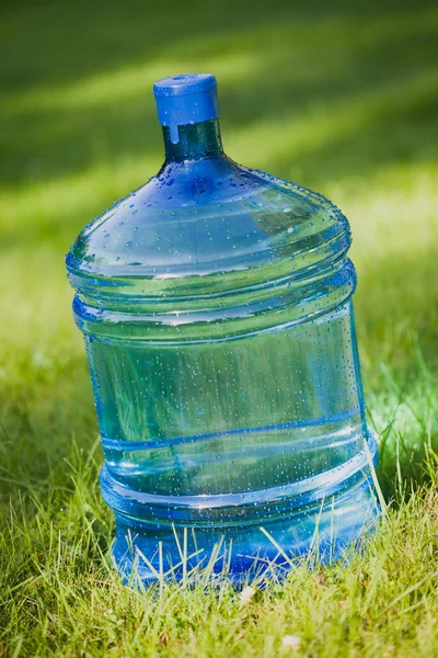 Water bottle on green lawn background — Stock Photo, Image