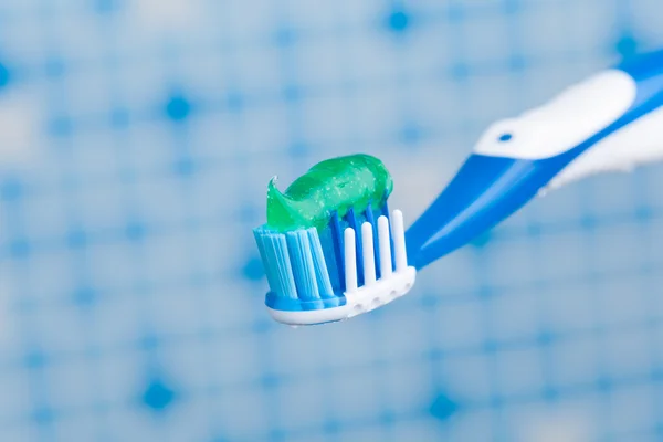 Зубная щетка на фоне синей плитки — стоковое фото