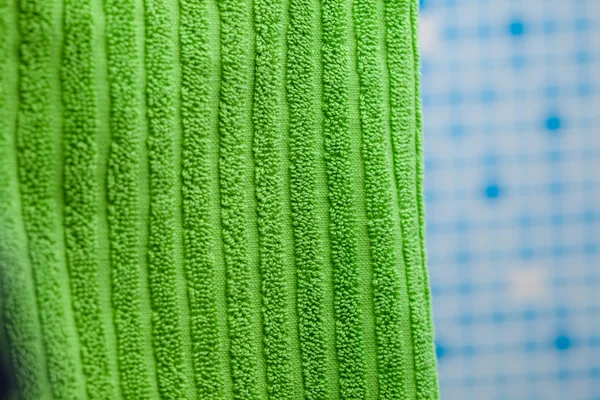 Asciugamano verde contro sfondo piastrelle blu — Foto Stock