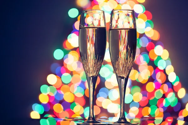 Champagne glasses against christmas tree bokeh lights — Stock Photo, Image