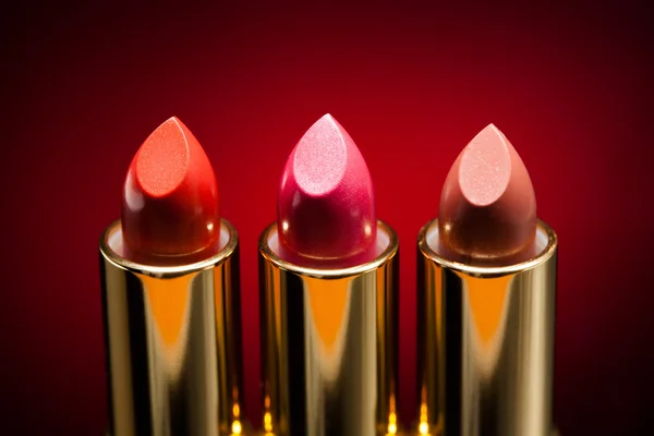 Three lipsticks on red background — Stock Photo, Image