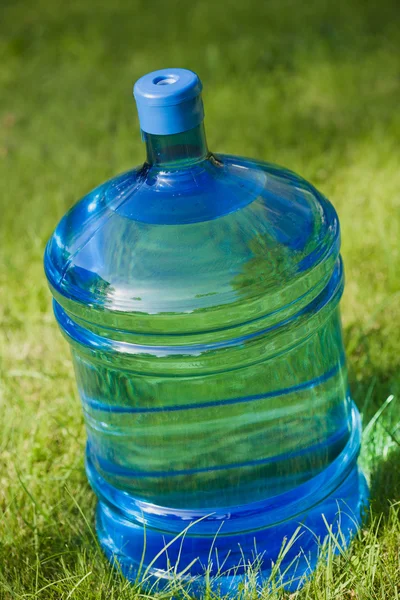 緑の草の背景に水の大きなボトル — ストック写真