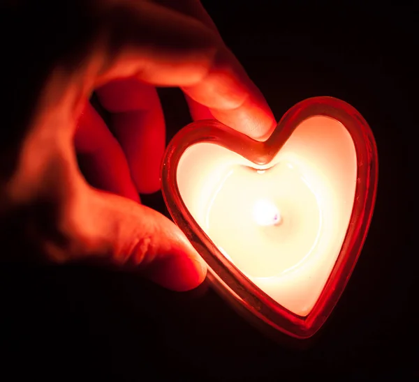 Mão segurando coração de vela ardente — Fotografia de Stock