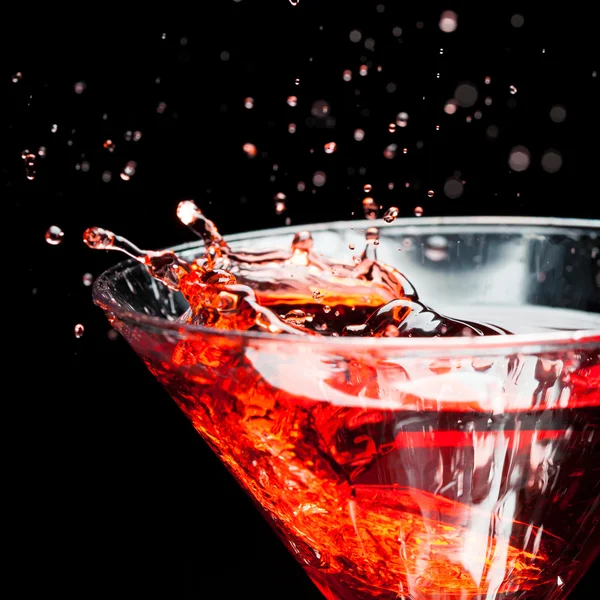 Red splashing cocktail on black — Stock Photo, Image