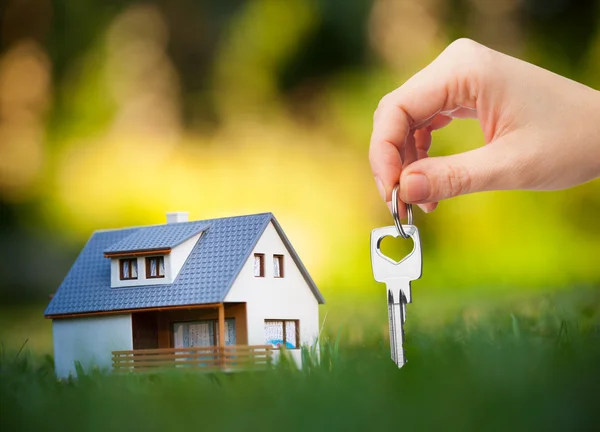 Hand holding key against house background — Stock Photo, Image