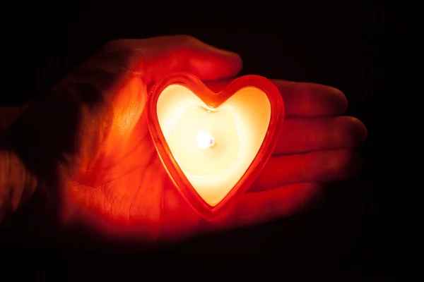 Corazón de vela ardiente en la mano — Foto de Stock