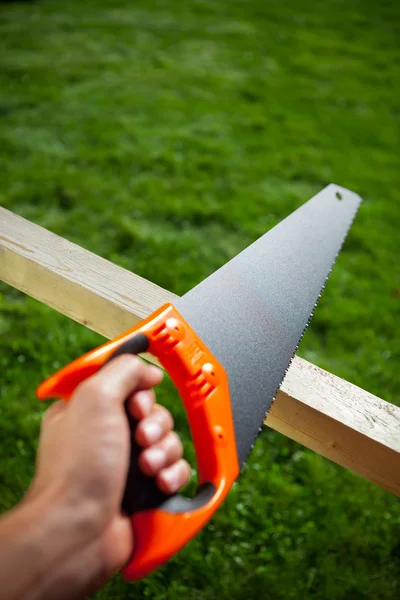 Cutting plank with hand saw — Stock Photo, Image