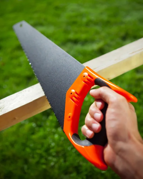 Cutting plank with hand saw — Stock Photo, Image