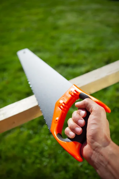 Cutting plank with hand saw — Stock Photo, Image