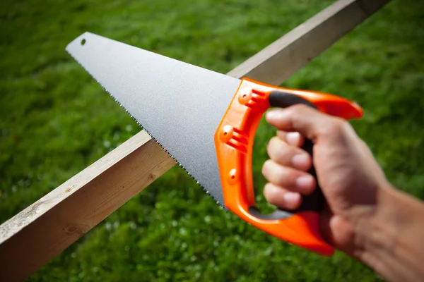 Cutting plank with hand saw — Stock Photo, Image
