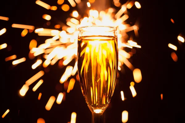 Champagnerglas vor weihnachtlichem Wunderkerzen-Hintergrund — Stockfoto