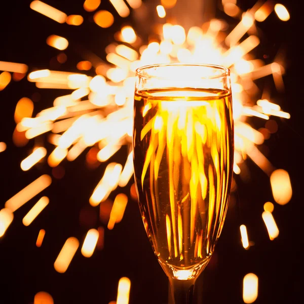 Champagnerglas vor weihnachtlichem Wunderkerzen-Hintergrund — Stockfoto