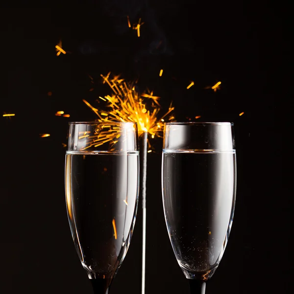 Champagne glasses against christmas sparkler background — Stock Photo, Image