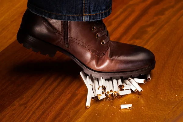 Shoes trampling down on cigarettes — Stock Photo, Image