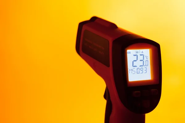 Инфракрасный лазерный термометр на оранжевом фоне — стоковое фото