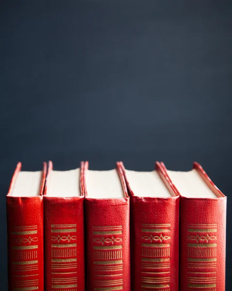 Red books against blue blackboard background — Stockfoto