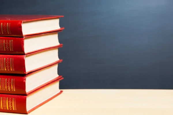 Red books against blue blackboard background — Stockfoto