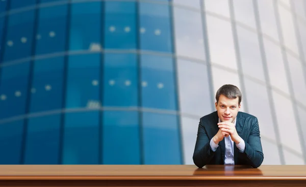 Business man against office windows background — Stock Photo, Image