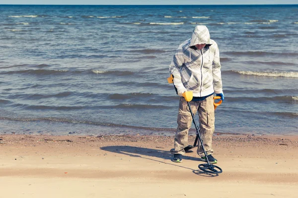 Hombre que busca un metal precioso usando un detector de metales — Foto de Stock