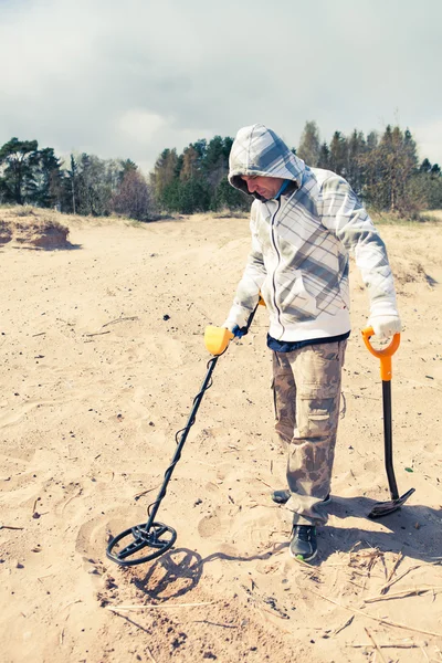 Uomo alla ricerca di un metallo prezioso utilizzando un metal detector — Foto Stock