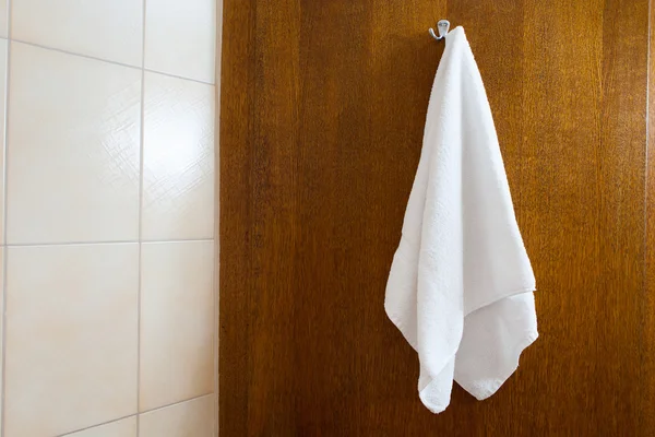 Towel hanging on the hook against brown wood background — Stock Photo, Image