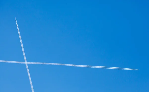 Piste di aeroplani attraversando contro sfondo cielo blu — Foto Stock