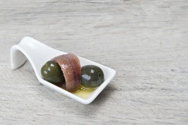 Anchovy and olives in a china spoon — Stock Photo, Image